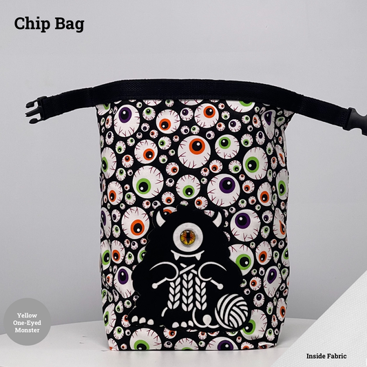 Eyeball-print Chip Bag featuring a black one-eyed monster with a yellow eye appliqué knitting beside a ball of yarn.